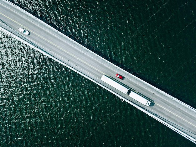 Luftbild von oben auf die Brückenstraße mit Autos über See oder Meer in Finnland