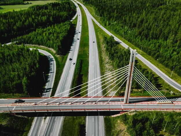 Luftbild von oben auf die Hängebrücke und die Autobahn mit grünen Wäldern an einem Sommertag in Finnland