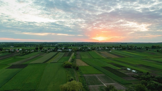 Luftbildlandschaft mit weitläufiger europäischer Landschaft mit Bauernhof und Land bei Sonnenuntergang am Sommertag