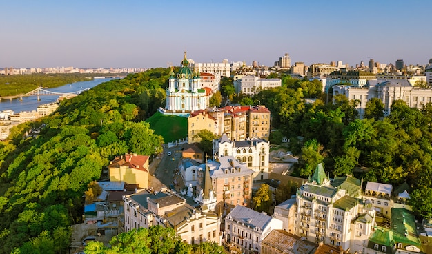 Luftbrummenansicht von St Andrew Kirche und von Andreevska-Straße von oben, Stadtbild von Podol-Bezirk auf Sonnenuntergang, Skyline der Stadt von Kiew (Kyiv), Ukraine