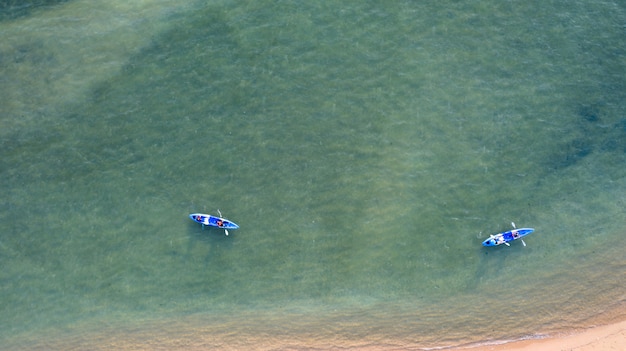 Luftdraufsicht von Kayak fahren um Meer mit blauem Wasser des Smaragdwassers und Wellenschaum