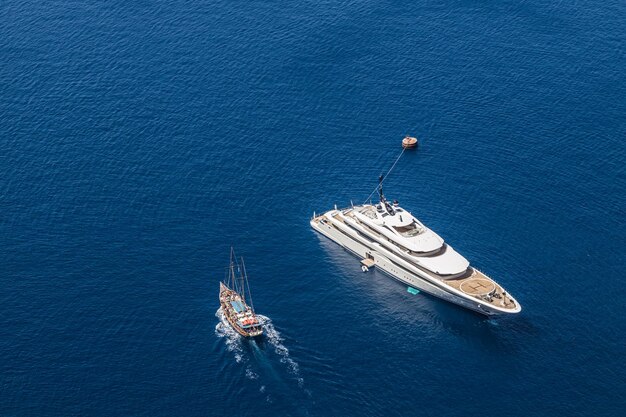 Luftdrohne von oben nach unten Foto einer Luxusyacht mit Holzdeck, das im offenen Ozean verankert ist