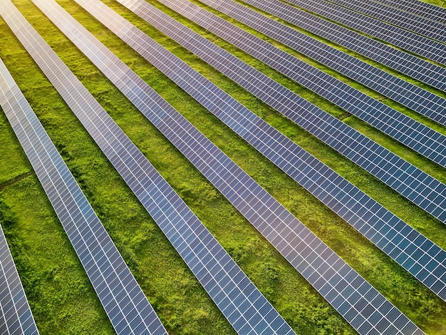 Luftdrohnenansicht des Solarkraftwerks in der grünen Wiese am sonnigen Tag