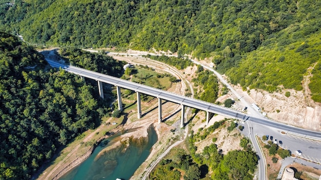 Luftdrohnenansicht einer Brücke über einem schmalen Fluss in Georgia. Tal, grüne Hügel