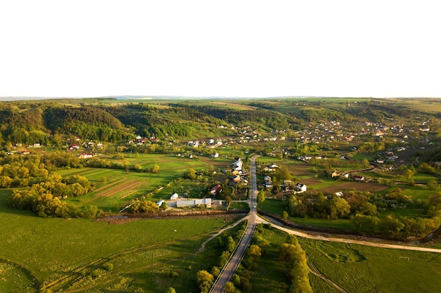 Luftlandschaftsansicht von Dorfhäusern und entfernten grünen bebauten landwirtschaftlichen Feldern mit wachsenden Ernten am hellen Sommertag