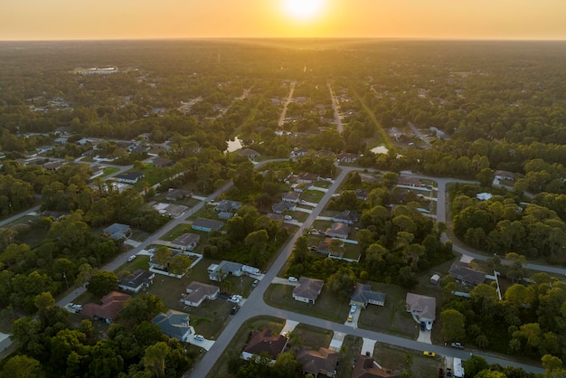 Luftlandschaftsansicht von vorstädtischen Privathäusern zwischen grünen Palmen in Floridas ruhiger ländlicher Gegend bei Sonnenuntergang