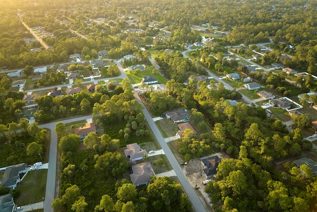 Luftlandschaftsansicht von vorstädtischen Privathäusern zwischen grünen Palmen in Floridas ruhiger ländlicher Gegend bei Sonnenuntergang