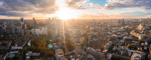 Luftpanorama des Londoner Finanzviertels mit vielen berühmten Wolkenkratzern in der Nähe der Themse bei Sonnenuntergang.