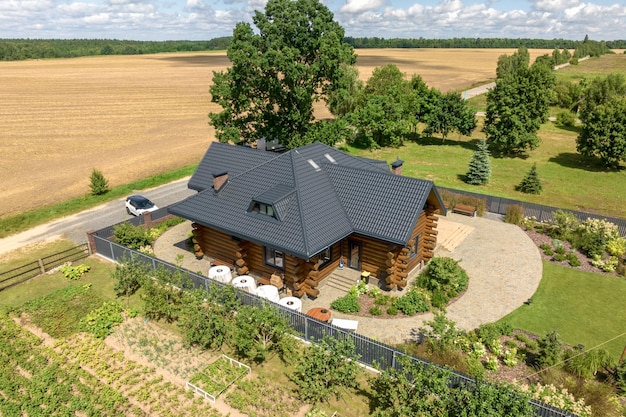 Luftpanoramablick auf hölzernes Ökohaus oder Gehöft im grünen Dorf