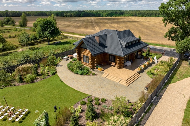 Luftpanoramablick auf hölzernes Ökohaus oder Gehöft mit Pool im grünen Dorf