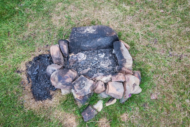 Lugar abandonado del fuego en el bosqueVieja chimenea quemada vieja hoguera abandonada en un prado de hierba