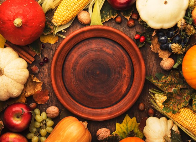 Lugar de la cena de acción de gracias Frutas de otoño calabazas nueces hojas caídas con plato y cubiertos Fondo de otoño de acción de gracias