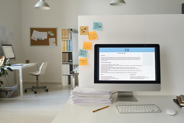 Lugar de trabalho de uma pessoa de negócios com computador com currículo on-line no monitor em um escritório moderno
