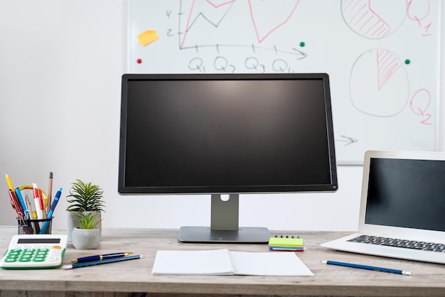 Lugar de trabalho sem pessoas computador portátil caneta bloco de notas e quadro branco com h gráfico de negócios mesa de escritório