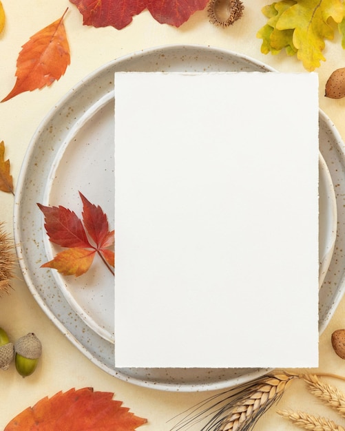 Lugar de mesa de otoño con hojas de colores y maqueta de vista superior de tarjeta en blanco vertical