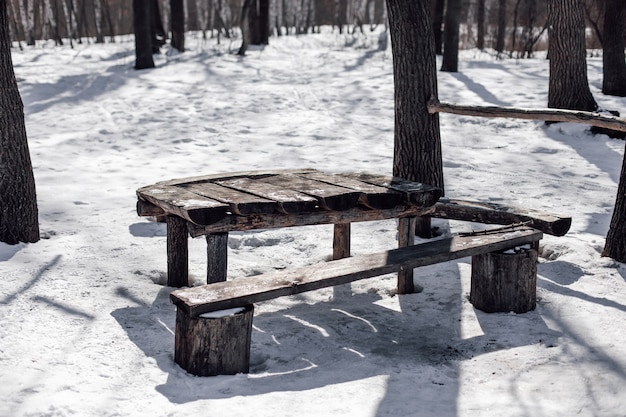 Lugar de picnic en el bosque mesa y banco de madera en el bosque nevado soleado mañana helada aftersnowfall