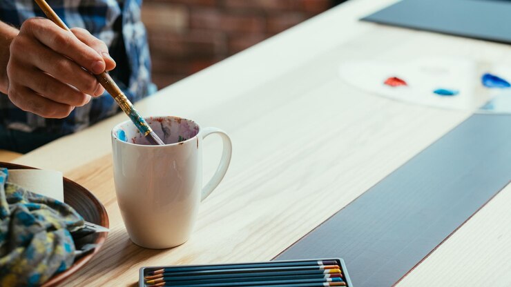 Foto lugar de trabajo del artista atmósfera de taller de estudio de arte hombre que sumerge el pincel en una taza blanca aprendizaje de pintura hobby ocio