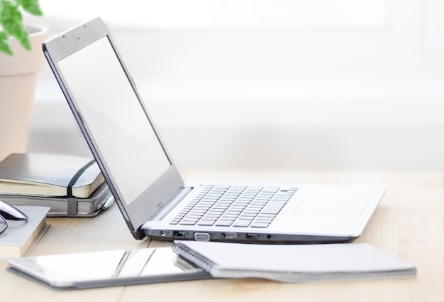 Lugar de trabajo en casa con ambiente agradable Laptop con pantalla vacía en blanco en el escritorio de casa