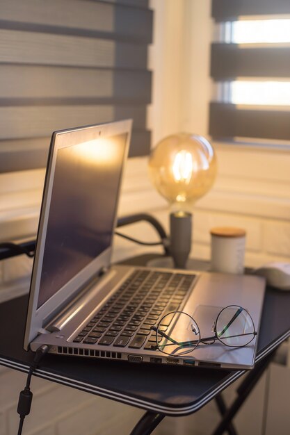 Lugar de trabajo en casa moderno de freelancer con lámpara amarilla y portátil en mesa negro