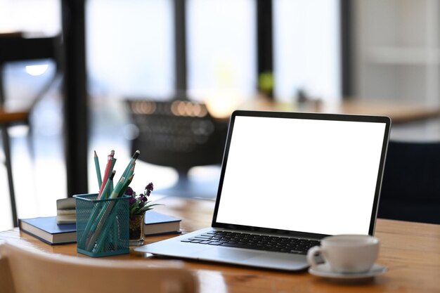 Lugar de trabajo cómodo con computadora portátil, portalápices y taza de café.