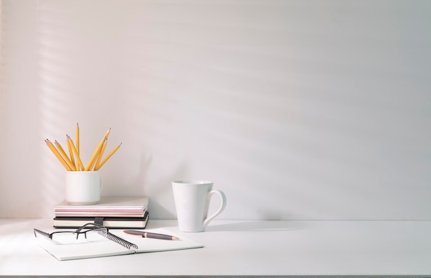 Lugar de trabajo cómodo con papelería de café y planta de interior en mesa blanca