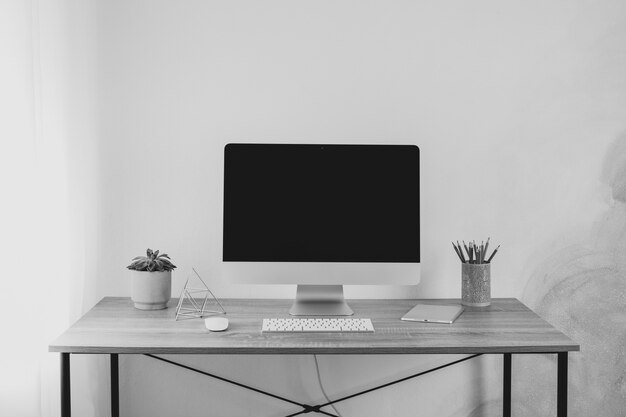 Lugar de trabajo con computadora, tableta y planta en mesa de madera, espacio para texto