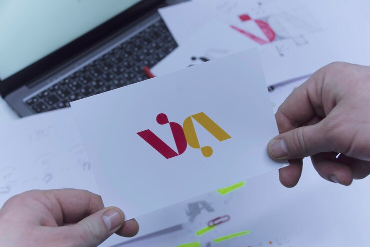 Foto lugar de trabajo creativo de un diseñador gráfico un hombre en la oficina está desarrollando un logotipo en la mesa contra el fondo de bocetos impresos y una computadora portátil