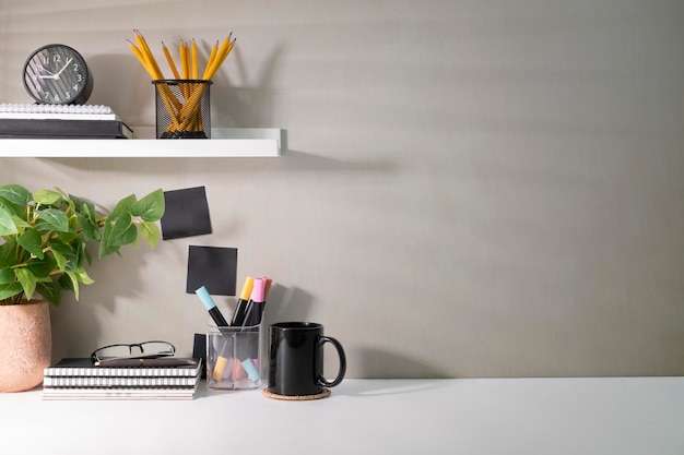 Lugar de trabajo creativo con plantas de la casa de suministros y taza de café en la mesa blanca Copie el espacio para su texto publicitario