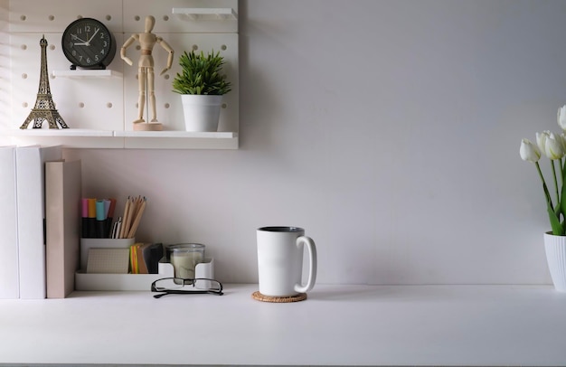 Lugar de trabajo creativo con plantas de la casa de suministros y taza de café en la mesa blanca Copie el espacio para su texto publicitario