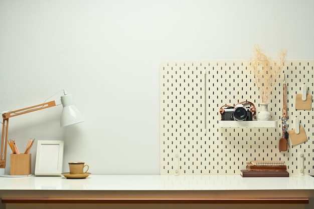 Lugar de trabajo elegante con lámpara de cámara de libros y tablero de clavijas en una mesa de madera contra el espacio de copia para su texto