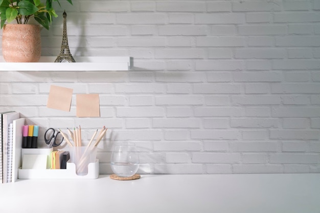 Lugar de trabajo elegante con marco de papelería planta de la casa y taza de café en la mesa blanca