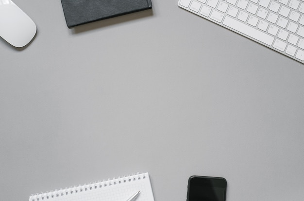 Lugar de trabajo de un empleado de oficina o autónomo con teclado, mouse, planeadores y diarios, bolígrafo, teléfono sobre un fondo gris con espacio de copia.