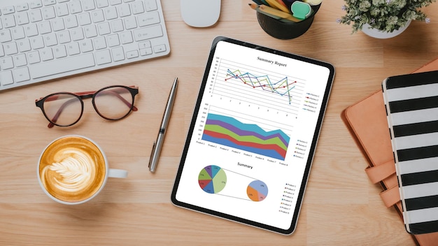 Lugar de trabajo de escritorio de oficina con gráficos e informes en la pantalla de la tableta Vista superior plana