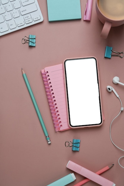 Foto lugar de trabajo femenino con portátil de teléfono inteligente y material de oficina sobre fondo rosa.