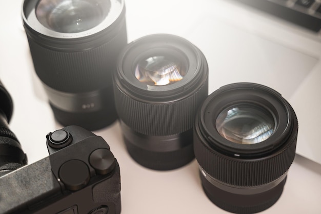 Lugar de trabajo del fotógrafo con un equipamiento moderno. Cámara sin espejo, portátil y lentes fijos.