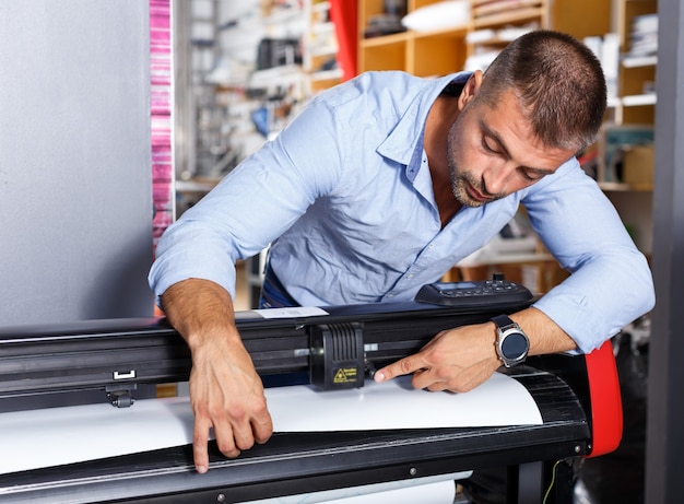 Lugar de trabajo de impresión de papel de trabajador masculino