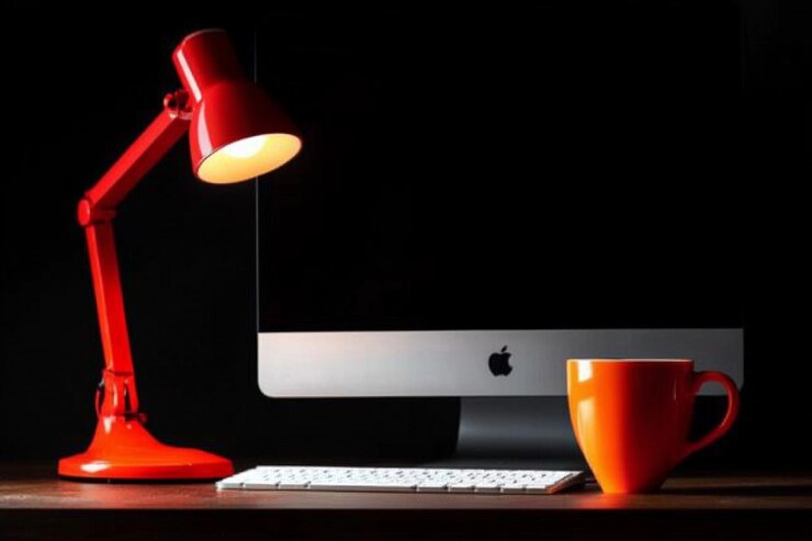 Foto lugar de trabajo con lámpara de computadora y taza de café en la mesa en una habitación oscura