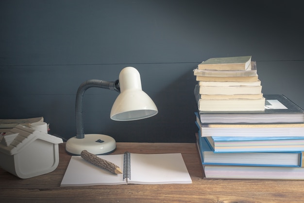 Foto lugar de trabajo con lámpara de lectura y libros sobre la mesa de madera vieja