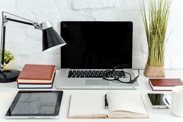 Lugar de trabajo con lo que necesitas. Primer plano de un cómodo lugar de trabajo en la oficina con una mesa blanca y un portátil tendido sobre él