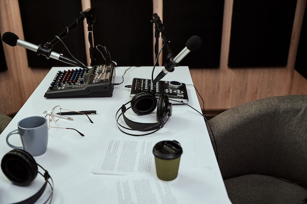 Foto lugar de trabajo de locutor de radio cerca de micrófonos auriculares mesa de mezclas de sonido script en el