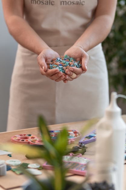 Lugar de trabajo del maestro del mosaico: manos de mujeres sosteniendo detalles de mosaico en el proceso de hacer un mosaico