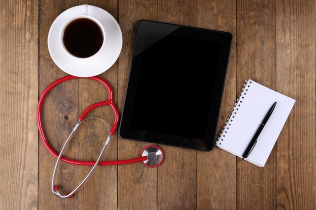 Lugar de trabajo médico con tableta en blanco y estetoscopio sobre fondo de madera