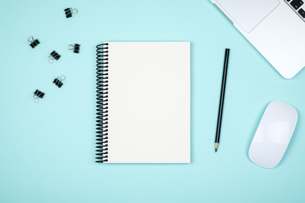 Lugar de trabajo mínimo con computadora portátil y bloc de notas en blanco
