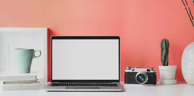 Lugar de trabajo mínimo con computadora portátil con pantalla en blanco abierta