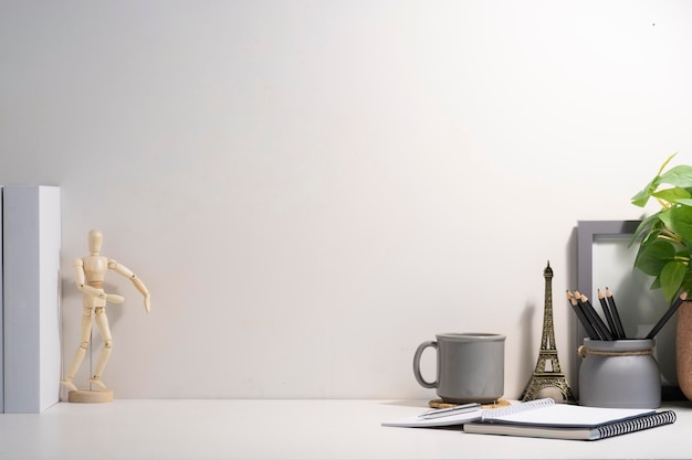 Lugar de trabajo mínimo con un marco de imagen vacío, una taza de café y un portalápices en una mesa blanca. Copie el espacio para su texto.