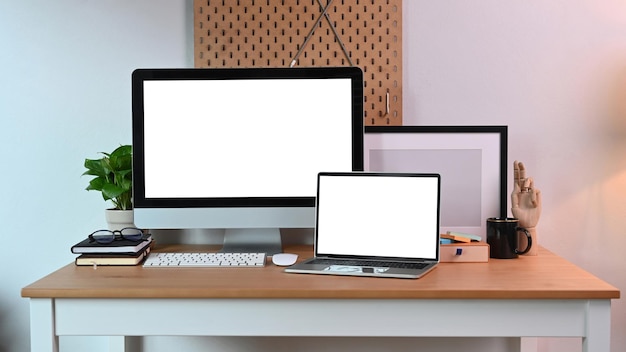 Lugar de trabajo moderno con computadora simulada y computadora portátil con pantalla blanca