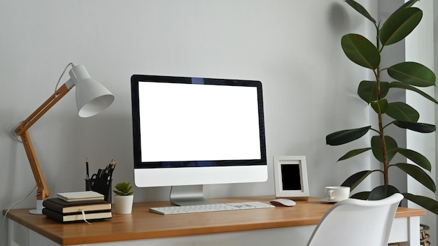 Lugar de trabajo moderno con lámpara de pantalla de computadora en blanco y suministros en escritorio de madera Pantalla vacía para su diseño publicitario