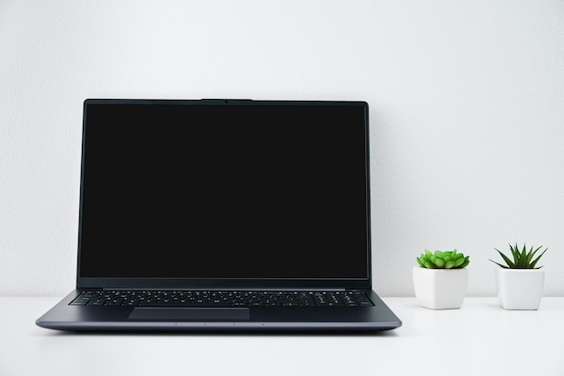 Foto lugar de trabajo de oficina con computadora portátil y plantas en la mesa interior de oficina