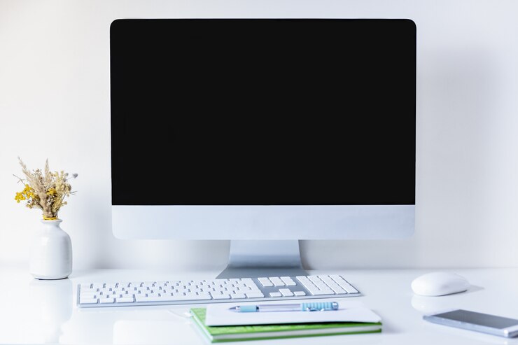Foto lugar de trabajo de oficina limpio y minimalista con computadora de escritorio. vista frontal de la pc, teléfono celular, papeles y teclado numérico en la mesa blanca limpia