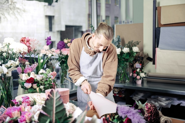 En el lugar de trabajo. Persona del sexo masculino guapo expresando positividad mientras trabajaba en la tienda de flores